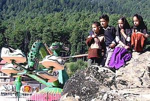 Two Kashmiri brothers and their twin sisters sit on a rock looking at rides inside Kashmir's first amusement park in Pahalgam.