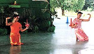 Ban Chang, Thailand. Two students perform traditional dance to celebrate Loy Kratong. In their left hands they hold a lotus flower containing a candle.
