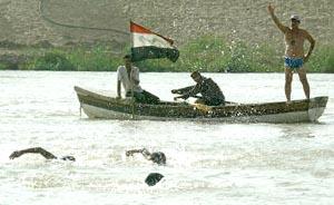 Iraqi coach of the Olympic swimming team, Said Jaafar (R), gives instruction to his team members from a row boat as they practice in the Tigris river in Baghdad