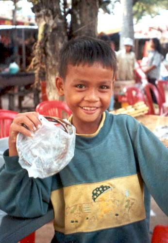 A boy helps his mother sell souvenirs near the front entrance to Angkor Wat.