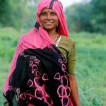 Bharatpur, Rajasthan, India: A colourfully sari-clad tribal lady cuts grass in Keoladeo Bird sanctuary.