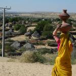 Ethnic Hindu woman carrying her matkas (water carriers) to her village below. 