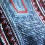 Indigo batik on embroidered cotton. The indigo has bled during repeated washes, reducing the contrast.    Batik "resist" designs are created by drawing with hot wax onto fabric. The fabric is immersed into dye, then the wax is removed, leaving the undyed parts visible.