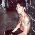 A young man with tattoos sits in the corner of a street in downtown Ho Chi Minh.