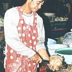 The coconut gets its head chopped with the cleaver. Then the two halves are ready for the flesh to be scraped out.