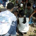 Dani Sirait visiting children at refugee camp in Keutapang, Banda Aceh city and distributing Orphans International shirts and chocolate wafers to the children.
