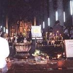 A man kneels in homage to the giant Buddha images at the back of the ordination hall.