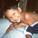 A young boy finds a huge bag of rice a perfect resting spot.