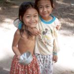 Two young girls stop to giggle at tourists in a Phnom Penh street.