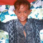 A young boy rigs a homemade tarp to use as shelter from an afternoon rainstorm.