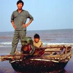 Two fishermen return to the beach in their lacquer boat.