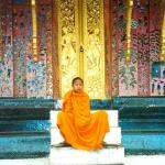 A monk rests on the steps of a pavilion at Wat Xiang Thong.