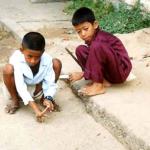 Two boys plan an intense game of marbles in a Phnom Penh street.