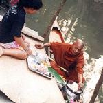A layperson offers food and flowers to a passing monk.